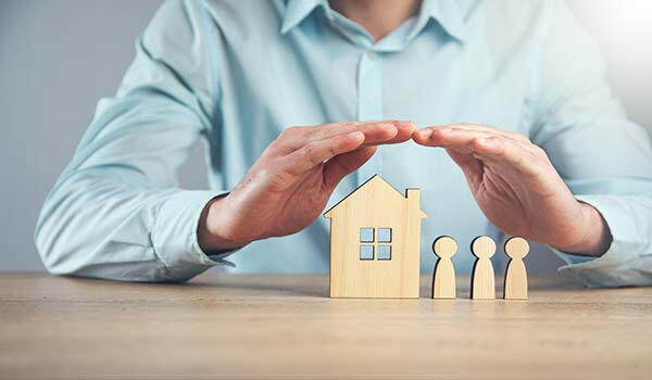 Hands covering a wooden house